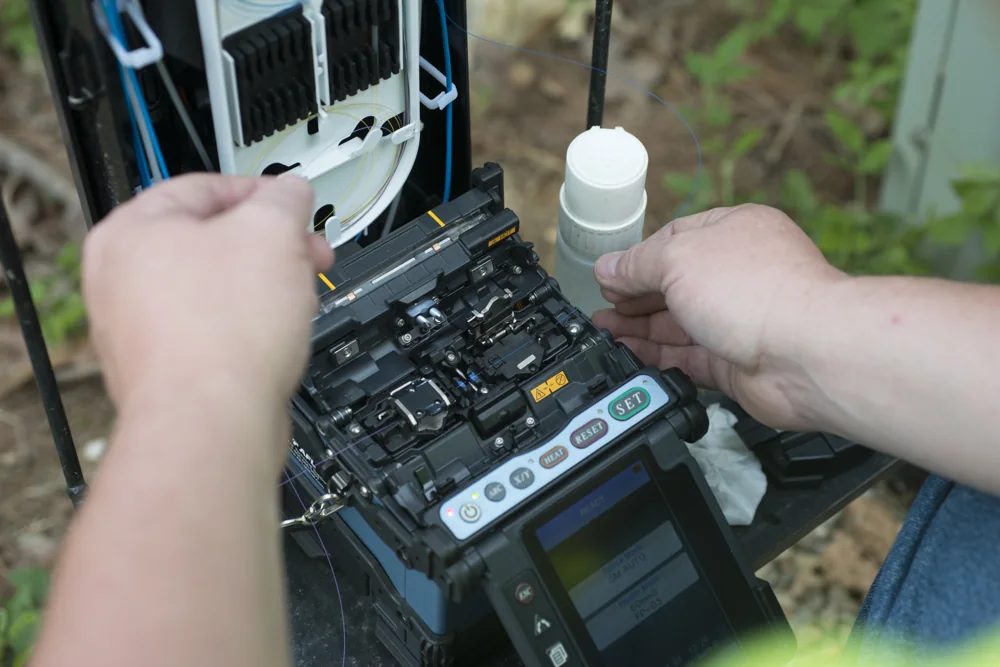 Técnico operando equipamento de fusão de fibra óptica